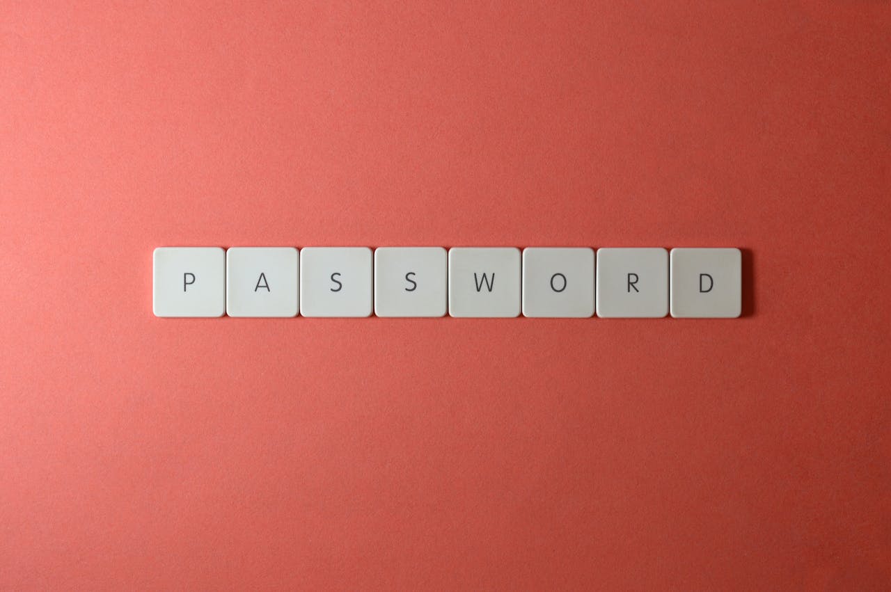 Focus on password security with white keyboard tiles spelling PASSWORD on a coral background.